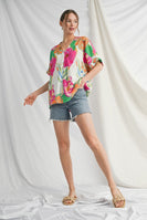 Woman wearing a colorful floral blouse and denim shorts on a white background