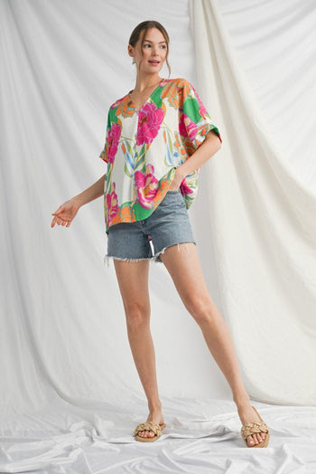 Woman wearing a colorful floral blouse and denim shorts on a white background