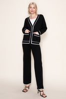 Woman wearing a black outfit with white trim on a plain background