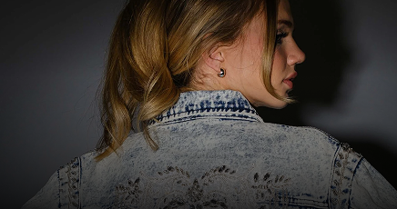 Person wearing a denim jacket with a dark background